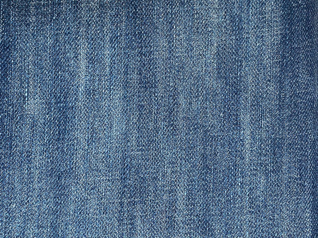 Close-up of blue denim fabric showing weave and stitching, a reference for judging jeans quality